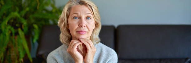 istock Middle-aged blond woman sitting on a sofa at home. 1221008685