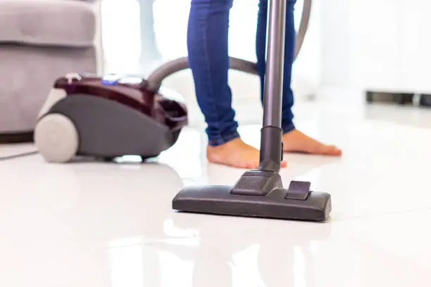 Vacuuming process. Cropped shot of woman legs cleaning floor of the house