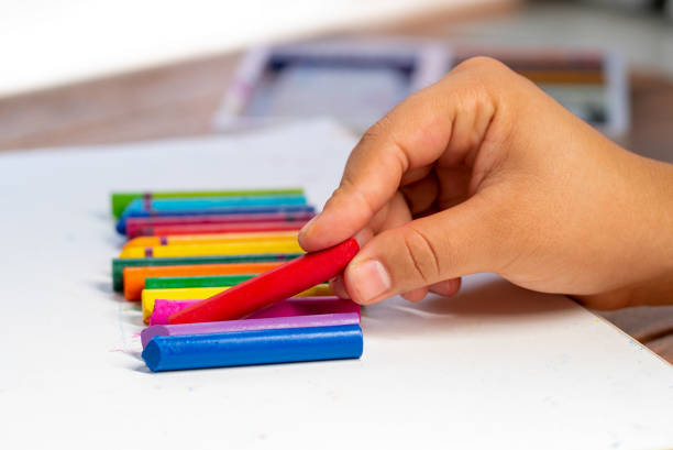 istock hand picks up a red wax crayon and many colors close 1221010947