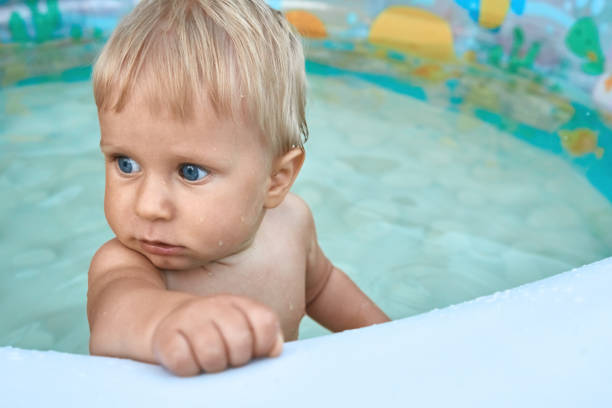 Beautiful one year old baby boy bathes in white Inflatable Swimming pool
