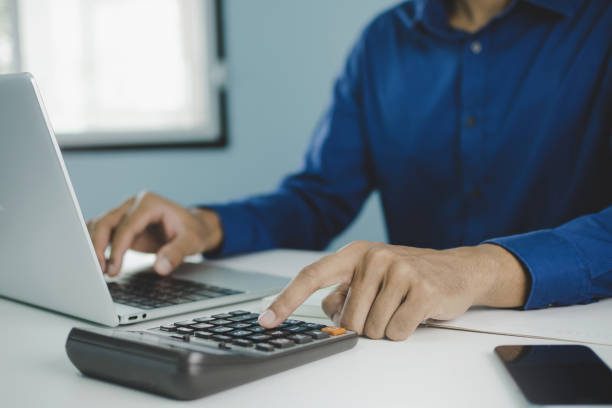 istock businessman working about finance on laptop computer with calculator, document report and mobile phone on desk at home, work from home, quarantine, technology, accountant, business financial concept 1221014396