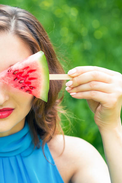 Woman covers eye with watermelon.