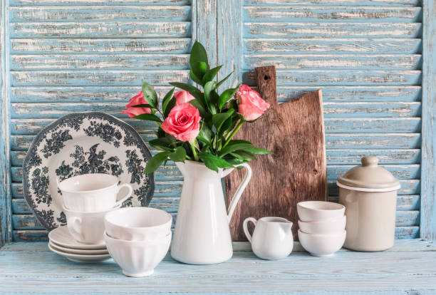istock Roses in a white pitcher, vintage crockery on blue wooden rustic background. Kitchen still life in vintage country style. Flat lay 1221017718