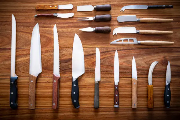 Photo of Kitchen knifes inventory on wooden backgroun in a row