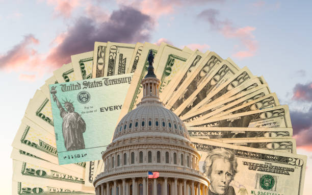 cúpula del capitolio del congreso de los estados unidos en dc con dinero en efectivo y cheque detrás del edificio como concepto para el pago del virus de estímulo - government spending fotografías e imágenes de stock