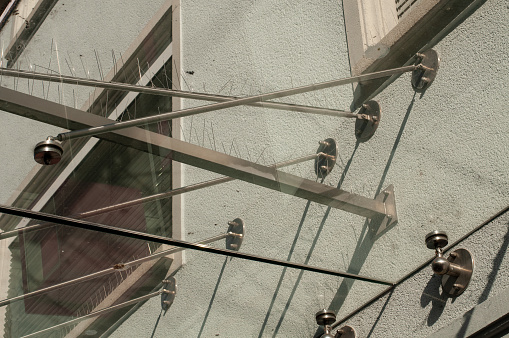 metal spikes for prevention of pigeons over a transparent porch on a facade of a building in pedestrian zone
