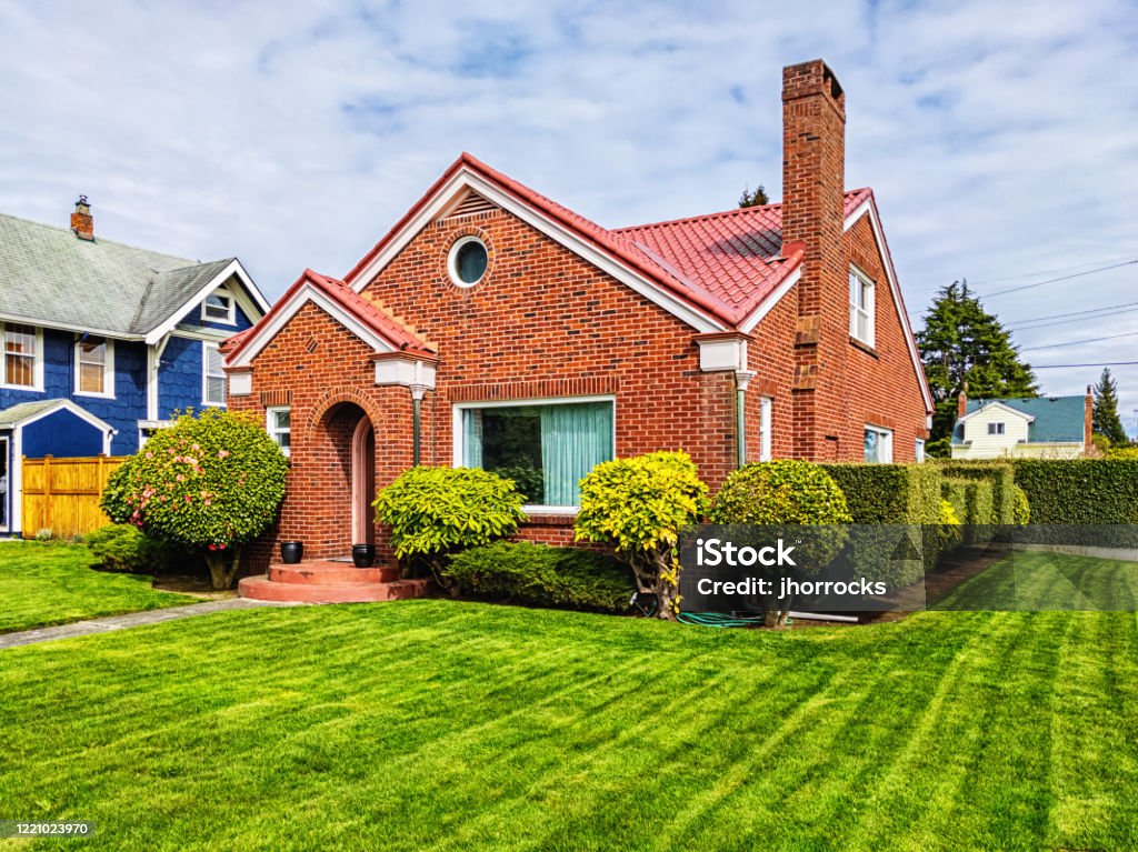 Small Red Brick House with Green Grass Photo of a small American red brick home on a sunny day House Stock Photo