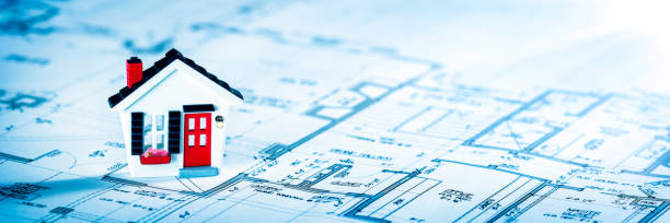 istock Miniature Toy House On Blueprint With Sunlight 1221024414