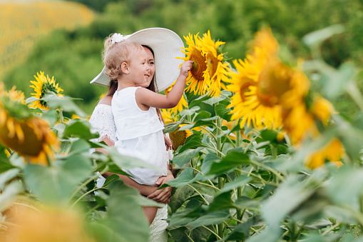 Happy mother with the daughter in the field with sunflowers. mom and baby girl having fun outdoors. family concept. selective focus.