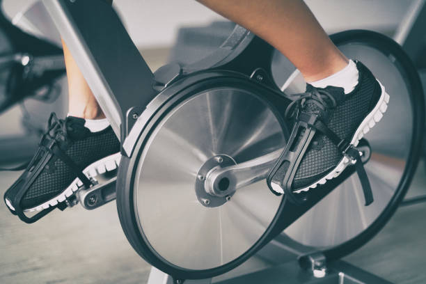 fitnessgerät zu hause frau radfahren auf indoor stationäre fahrrad übung drinnen für cardio-training. nahaufnahme von schuhen auf dem fahrrad - bicycle cycling exercising riding stock-fotos und bilder