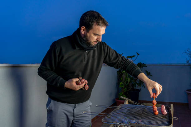 Bearded man preparing a barbecue at night on the terrace
