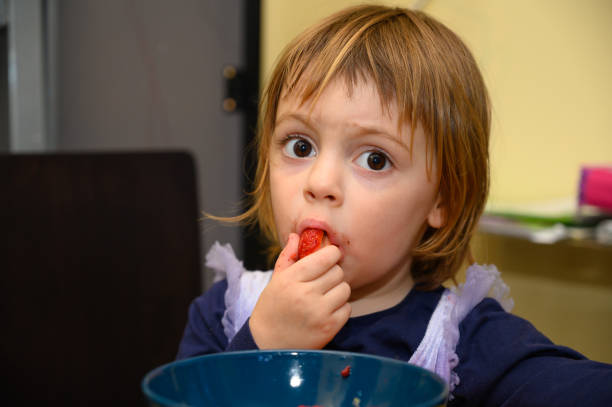 istock Girl eating strawberries 1221026096
