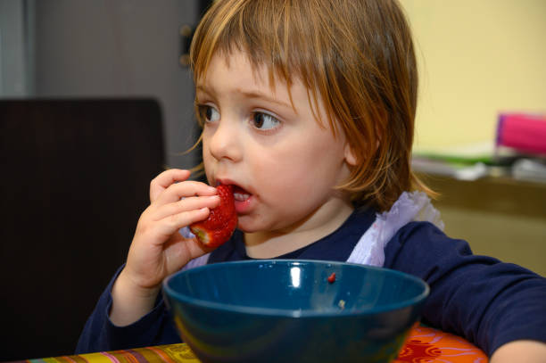 istock Girl eating strawberries 1221026939
