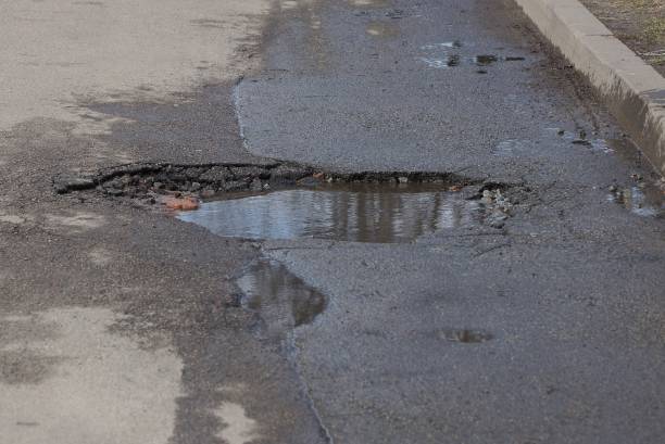 istock one large pothole with a puddle and brown dirty water 1221027151