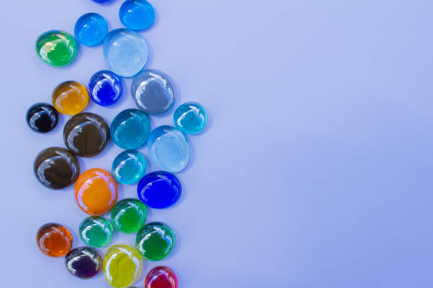 This images shows an abstract design background of colorful glass bead dragon tears on a light blue background, with copy space.