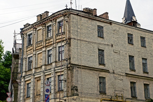 facade of a large brown old brick house with a row of windows against a gray sky