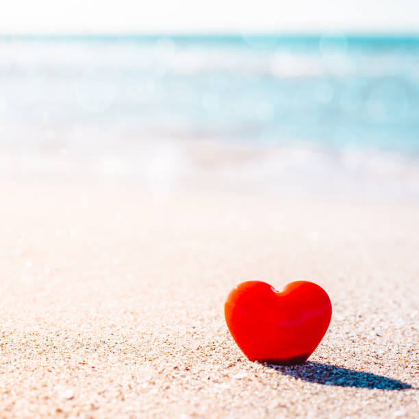 istock Romantic symbol of red heart on the sand beach 1221027778