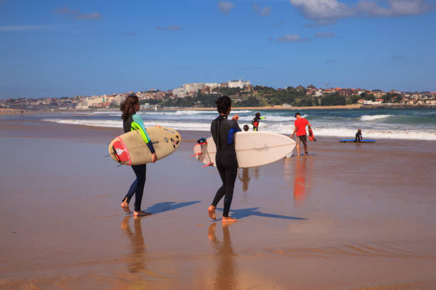 couples de surfeurs portant leur planche de surf sur la plage - surfing teenage girls friendship sunset photos et images de collection