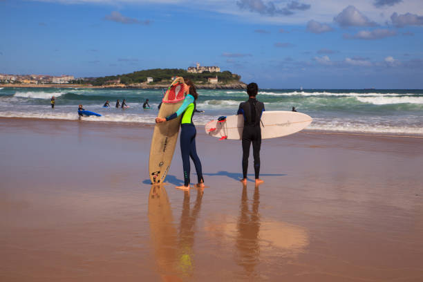 El Puntal, Somo, Spain - August, 20: Surfer couple carrying their surfboard on the beach on August 20, 2016