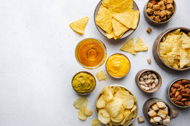 Veraity bowls of beer snacks Veraity bowls of beer snacks and sauces on stone table. Nuts, chips, nachos, crackers. Top view with copyspace pub table top view stock pictures, royalty-free photos & images