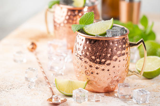 Cold Moscow Mules cocktail Cold Moscow Mules cocktail with ginger beer, vodka, lime. White stone background. mule stock pictures, royalty-free photos & images