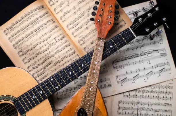 Mandolin and guitar with old blurred sheet music books in the background.