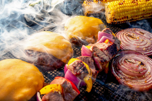 Lean Healthy Cheeseburgers, Kebobs, Onion Slices and Ears Of Corn On A Charcoal Grill Cheeseburgers, Kebobs, grilled corn, red onion, red and yellow peppers on a smokey grill metal grate photos stock pictures, royalty-free photos & images