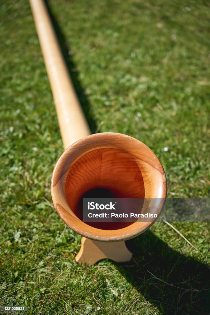 Close up view of a wooden Alpine horn (also Alphorn or Alpenhorn), a straight several-meter-long wooden natural horn of conical bore, with a wooden cup-shaped mouthpiece. Close up view of a wooden Alpine horn (also Alphorn or Alpenhorn), a straight several-meter-long wooden natural horn of conical bore, with a wooden cup-shaped mouthpiece. Portrait format. Yodeling Stock Photo
