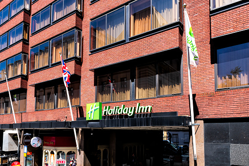 London, UK - June 22, 2018: Berkeley street in downtown Mayfair with sign for Holiday Inn hotel building and flags