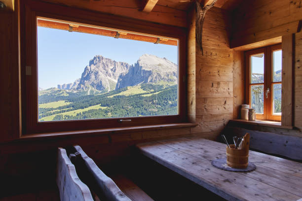 splendid view of the dolomites mountains from a window of a typical wooden cottage in the seiser alm (alpe di siusi in italian). - home interior cabin shack european alps imagens e fotografias de stock