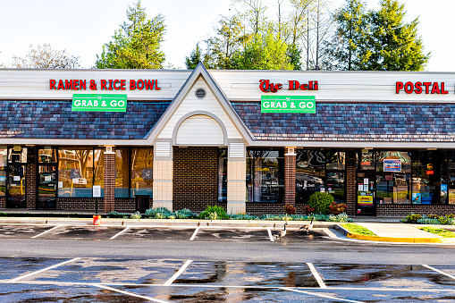 Herndon, USA - April 9, 2020: Strip mall plaza on street in Virginia Fairfax County with sign and entrance for restaurants and grab and go take out during coronavirus