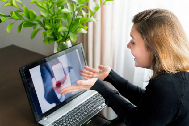 istock Online video call,marriage proposal to girlfriend.Laptop, computer.Engagement,wedding.Diamond ring in red box. Man:will you marry me.Surprised, shocked woman says yes. Quarantine,coronavirus covid-19 1221040900