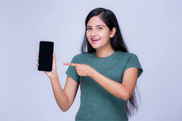 девушка с мобильным телефоном на белом фоне - teenage girls studio shot looking at camera waist up стоковые фото и изображения