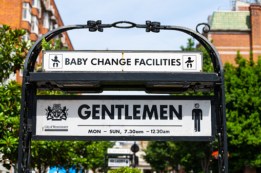 London, UK - June 24, 2018: Bayswater area road street and sign for baby changing station facilities and men's gentlemen bathroom restroom in summer closeup