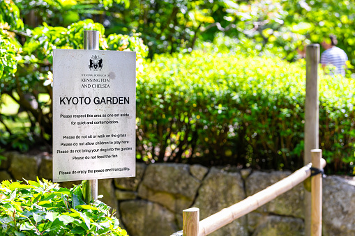 London, UK - June 24, 2018: Green trees foliage and sign for Kyoto Japanese Garden in Holland Park in summer with rules and regulations