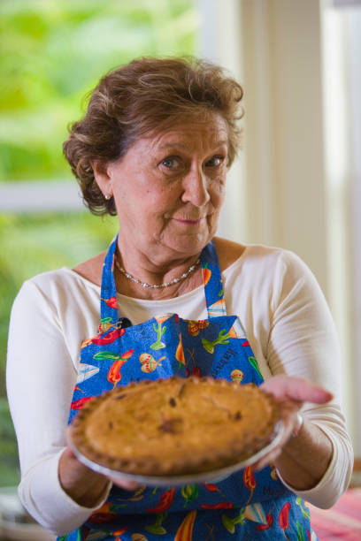 istock Senior woman holding apple pie in the kitchen 1221045802
