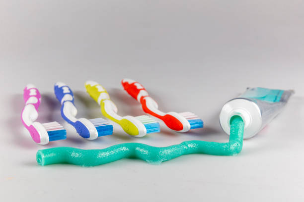 Toothbrushes and green toothpaste on white background.