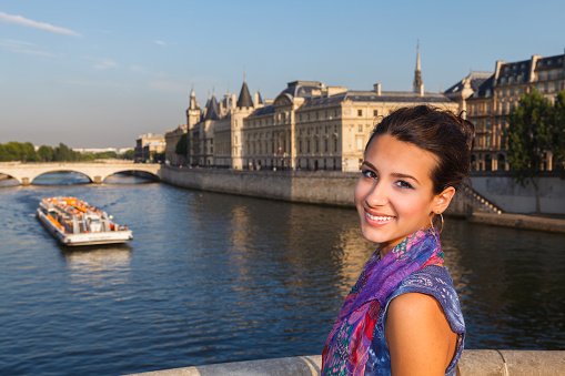 Beautiful young woman enjoying the sights of Paris by the River Seine at sunset.