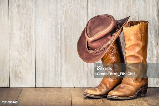 Wild West Retro Cowboy Hat And Pair Of Old Leather Boots On Wooden Floor Vintage Style Filtered Photo Stock Photo - Download Image Now