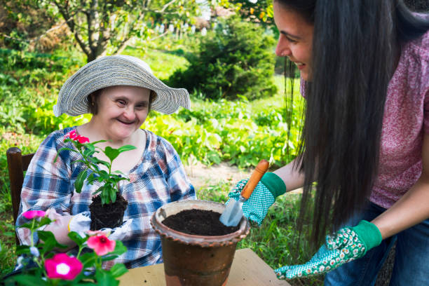kvinna med downs syndrom och hennes vän plantera blommor tillsammans. aktiviteter under covid-19 på bakgården - downs syndrome work bildbanksfoton och bilder