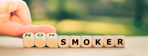 Stop smoking concept. Hand turns dice and changes the word "smoker" to "non smoker". stock photo