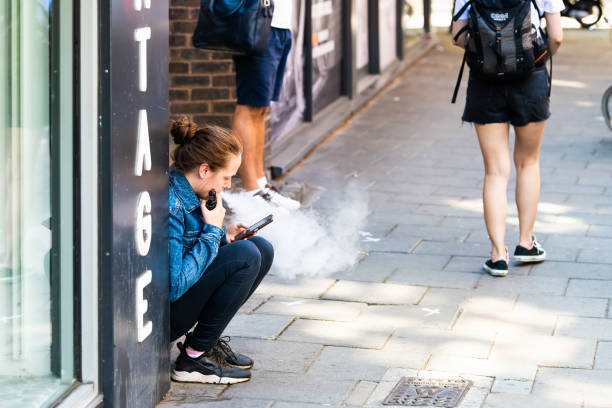 mulheres sentadas na calçada da rua em covent garden cidade vaping com vapor de cigarro eletrônico - quit scene - fotografias e filmes do acervo