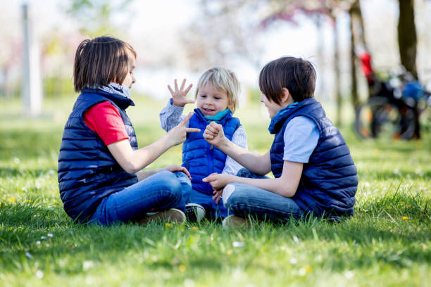 tre bambini, fratelli maschi, che giocano a giochi di carta con forbici da roccia - paper match foto e immagini stock