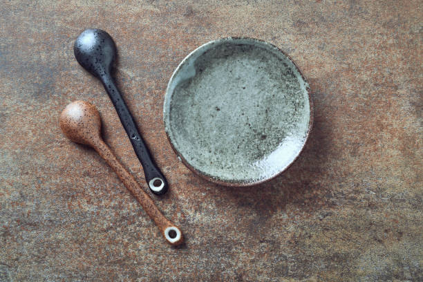 Empty ceramics plate and spoon on rustic stone background. Top view. Copy space.