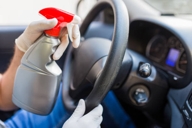 istock Man with rubber gloves using spray bottle sanitizer to protect car steering wheel from bacteria. Antiseptic, hygiene and healthcare concept. 1221055777