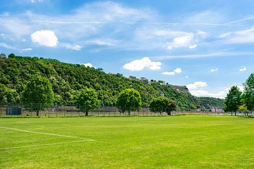 A football field located between the hills on a beautiful spring day, in the background a blue sky with white clouds.