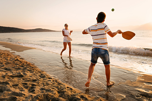 Teenage girl and boy playing beach tennis on sand