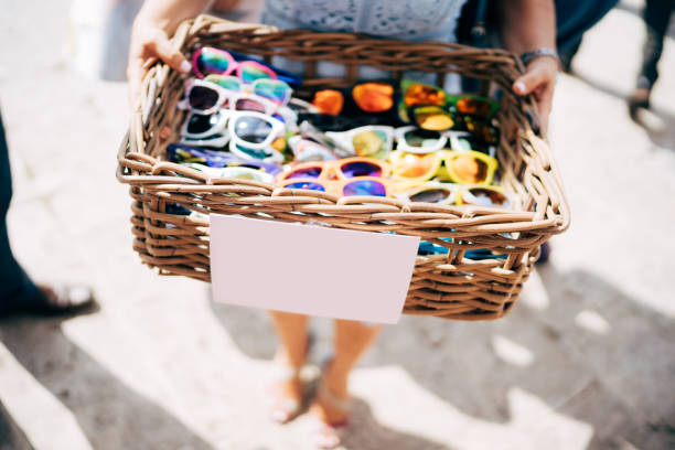 un panier de lunettes. un panier en osier de bois avec des lunettes de soleil de différentes couleurs dans les mains d’une fille. - placard holding celebration women photos et images de collection