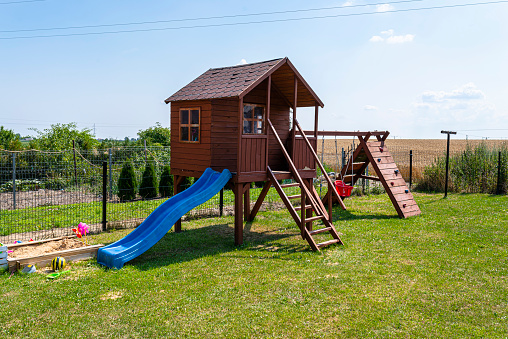 A side view of two sisters playing on a seesaw as the older one is at the bottom and the smaller one at the top on a sunny day at the park.