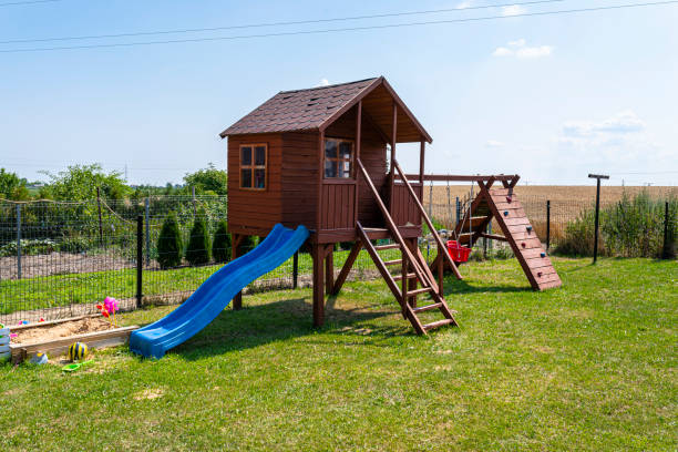 Childrens playground by the house garden, visible wooden house, beautiful spring day. Childrens playground by the house garden, visible wooden house, beautiful spring day. swing play equipment stock pictures, royalty-free photos & images